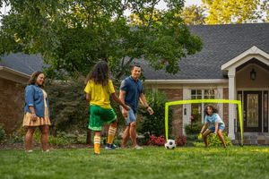 Family playing soccer together in the front yard.